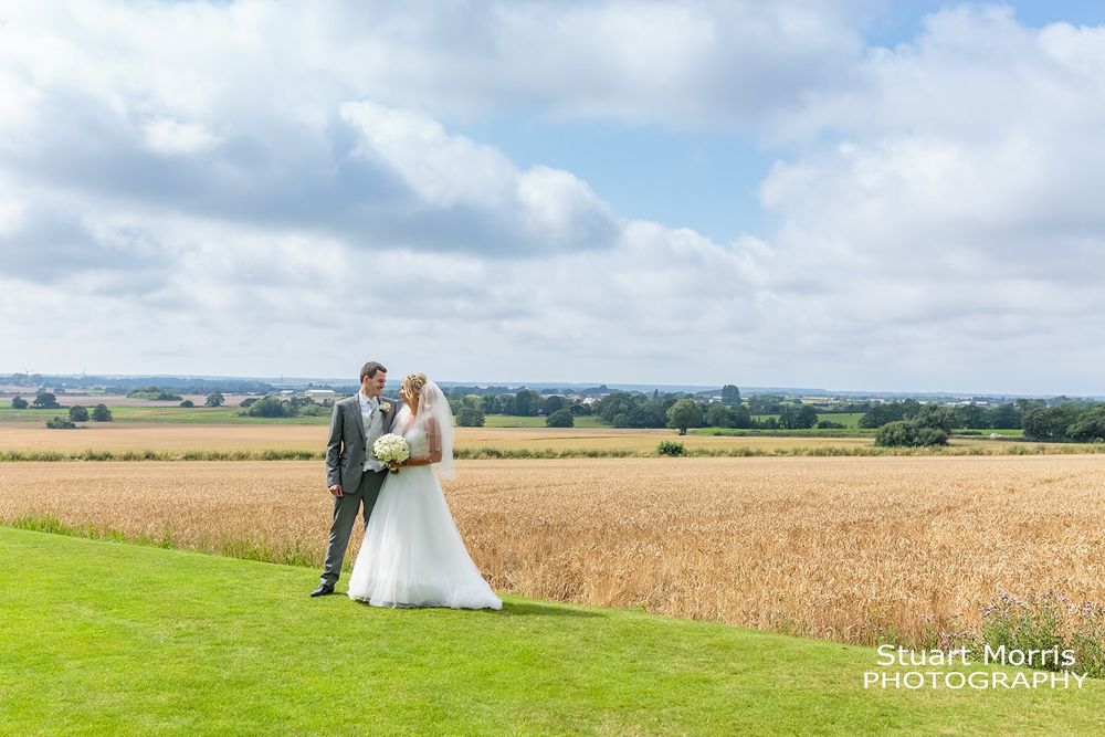 Bride and groom in the grounds at west tower country house, rolling Lancashire fields  behind them