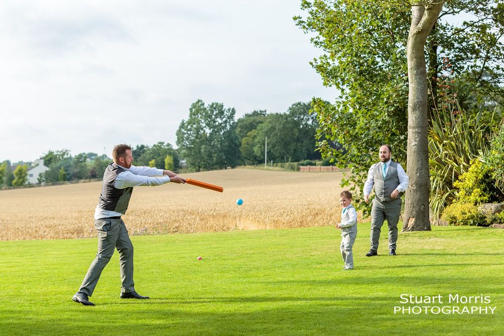Wedding guests playing cricket in the gardens at west tower country house. Lancashire wedding photographer