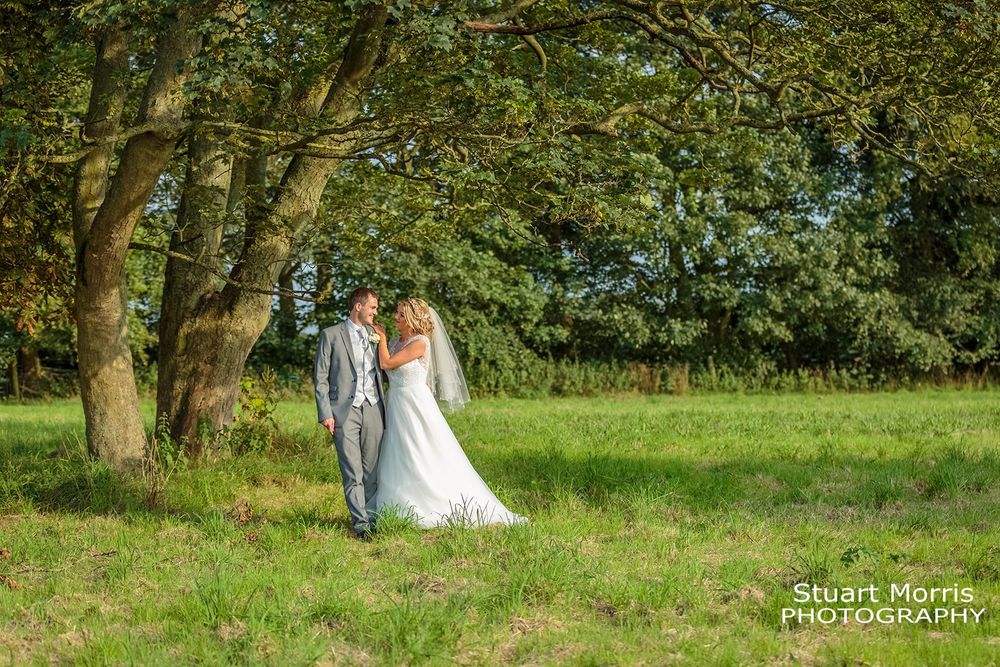 Bride and groom stand u set a tree in the meadow at west tower country house wedding venue.