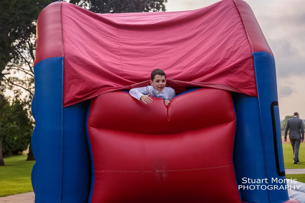 Young wedding guest climbs out the top if a bouncy castle. West tower wedding photographer
