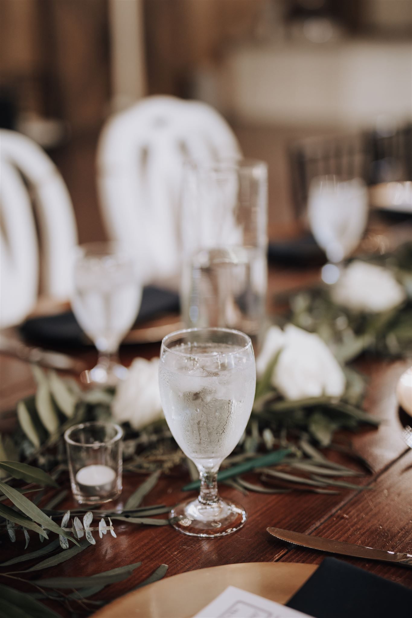 Elegant table setting with frosted water glass and eucalyptus greenery garland.
