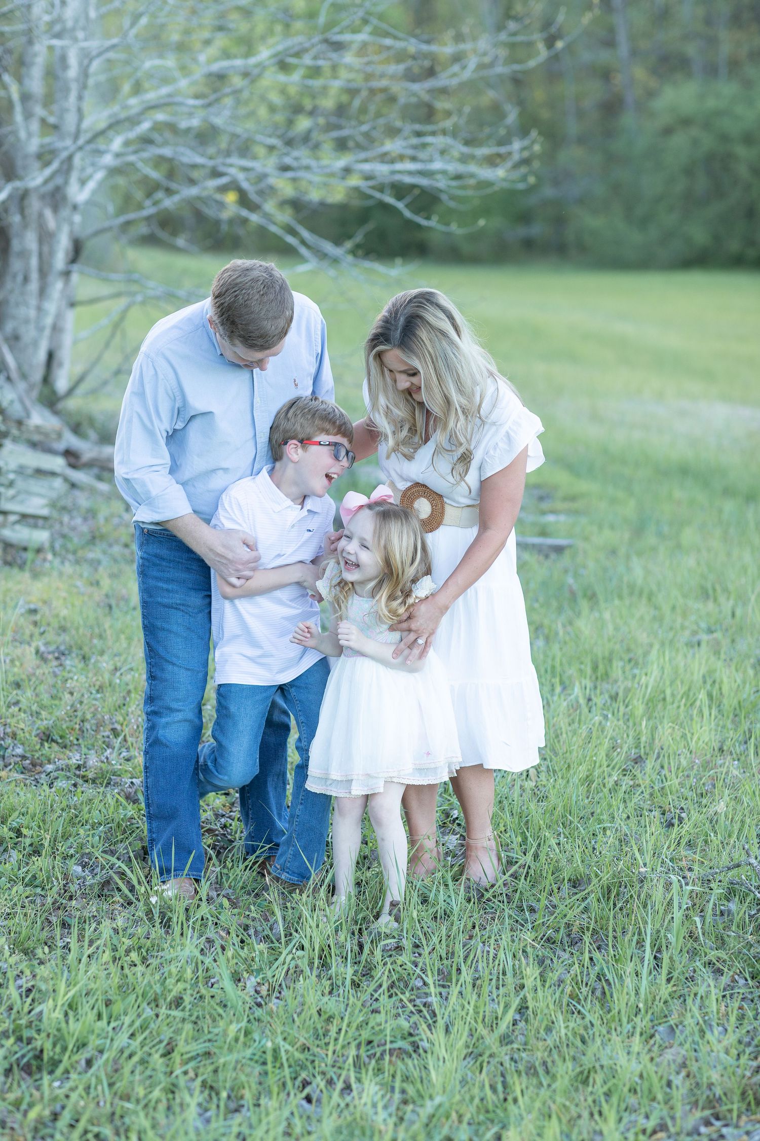 Family gathers in grassy field wearing coordinated white and blue outfits.