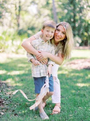 Playful embrace between parent and child outdoors in natural setting.
