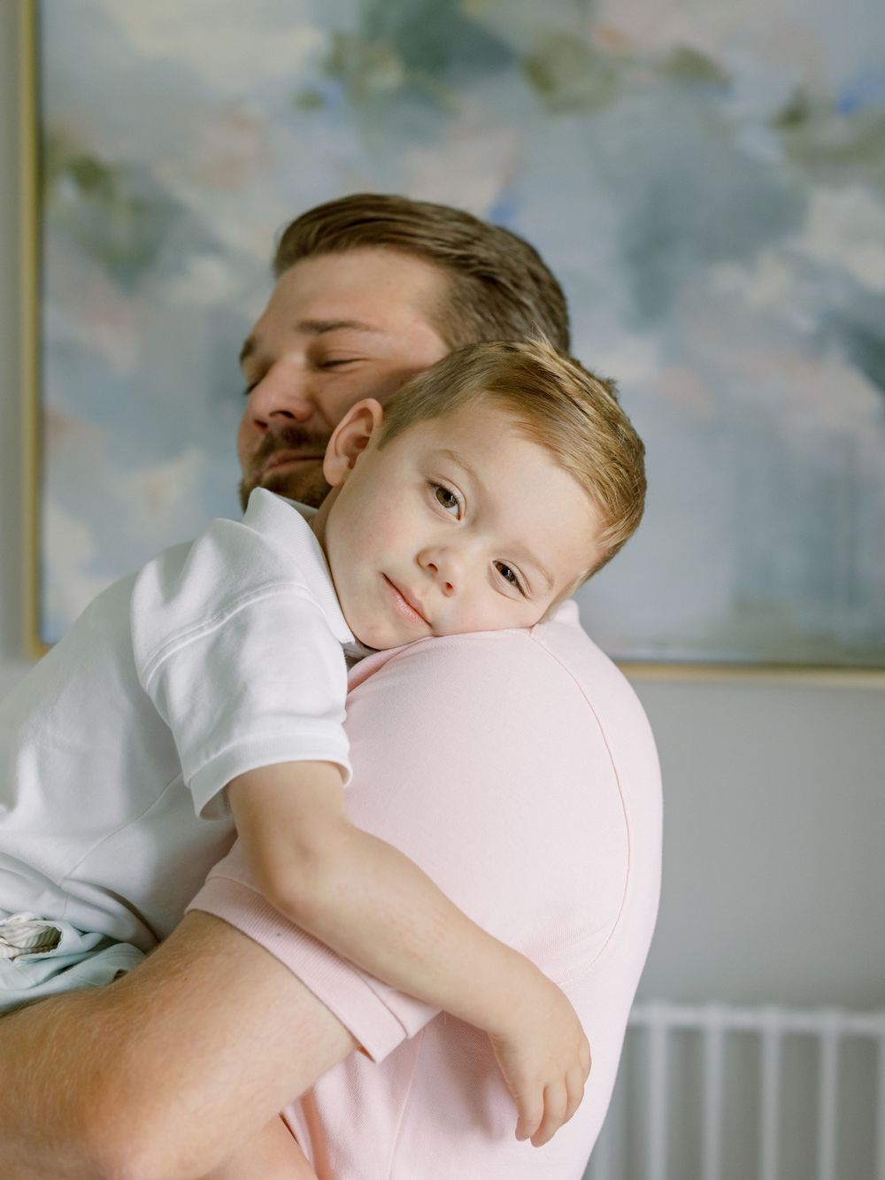 A sweet embrace between parent and child against a cloudy wallpaper background.