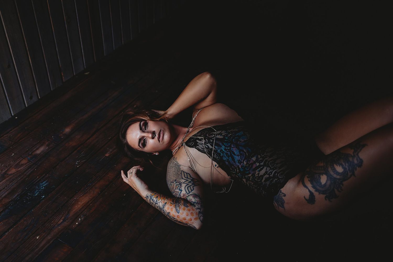 Seductive boudoir photography series with dramatic dark lighting and wooden backdrop.
