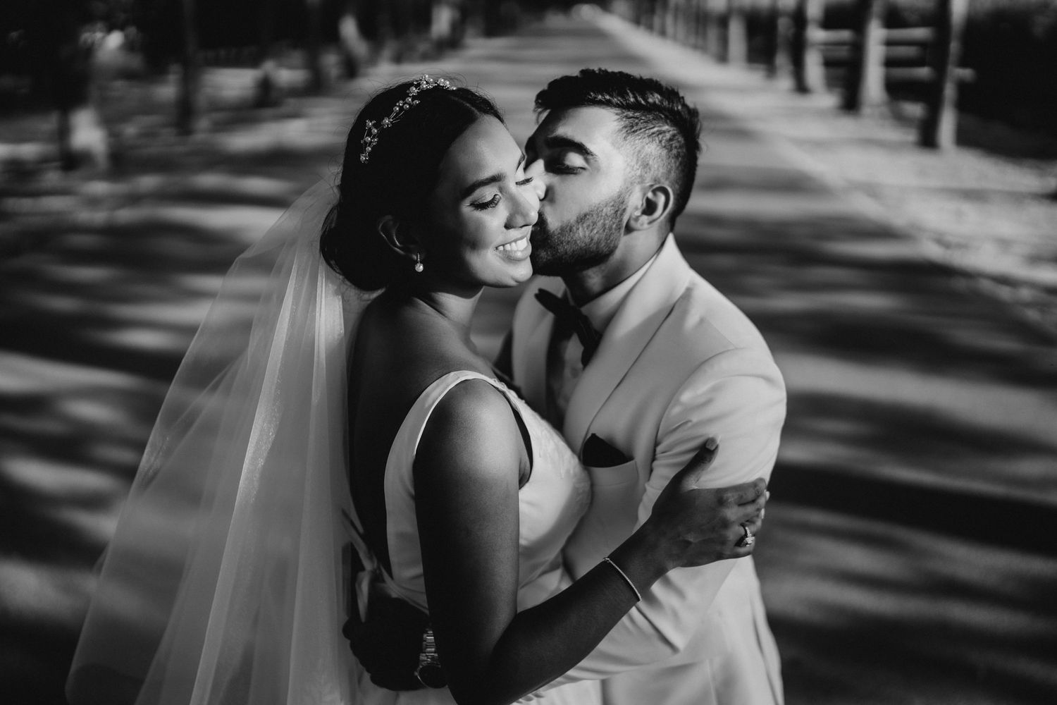 An intimate black and white wedding portrait in dappled sunlight.