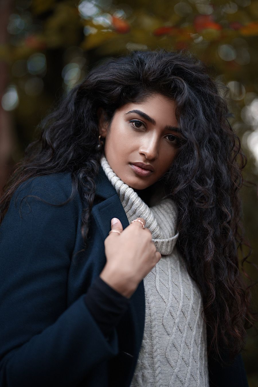Portrait of person in winter attire with flowing dark hair and turtleneck sweater.