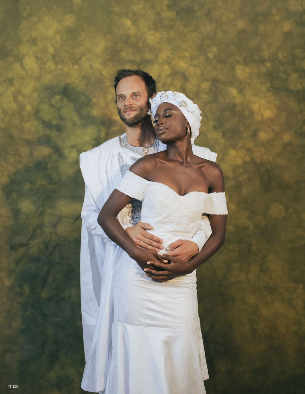 Elegant wedding portrait with couple in white against warm golden background.