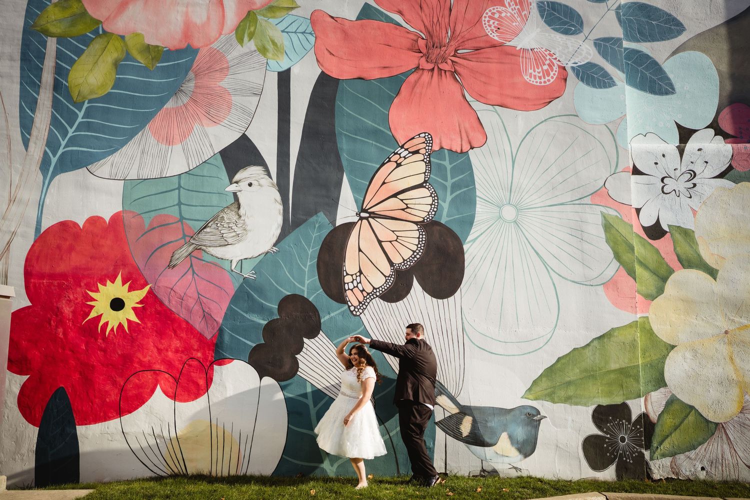 Silhouettes against vibrant floral mural with butterflies and blooms.