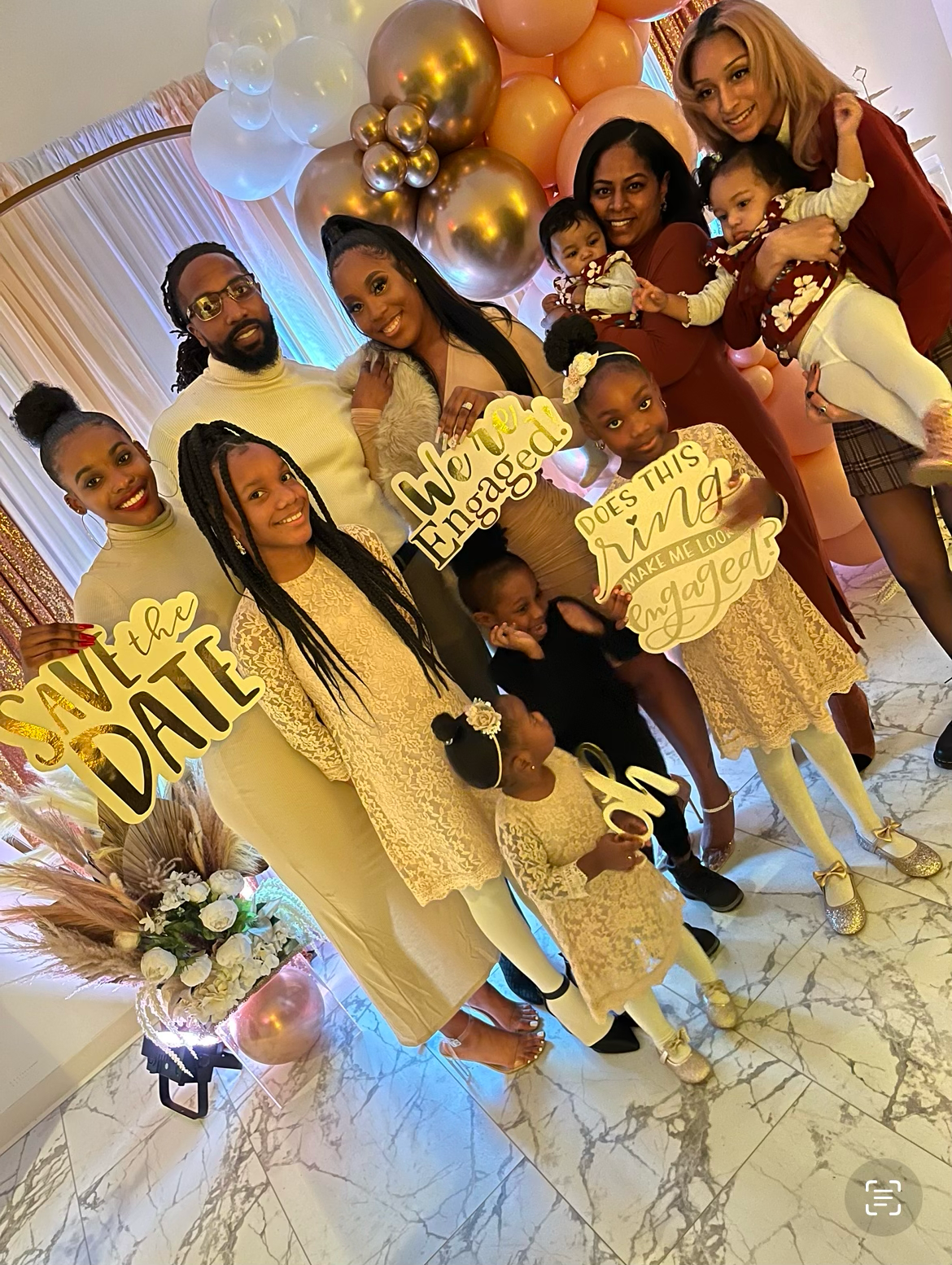 Celebratory gathering with gold and peach balloon decorations and matching outfits.
