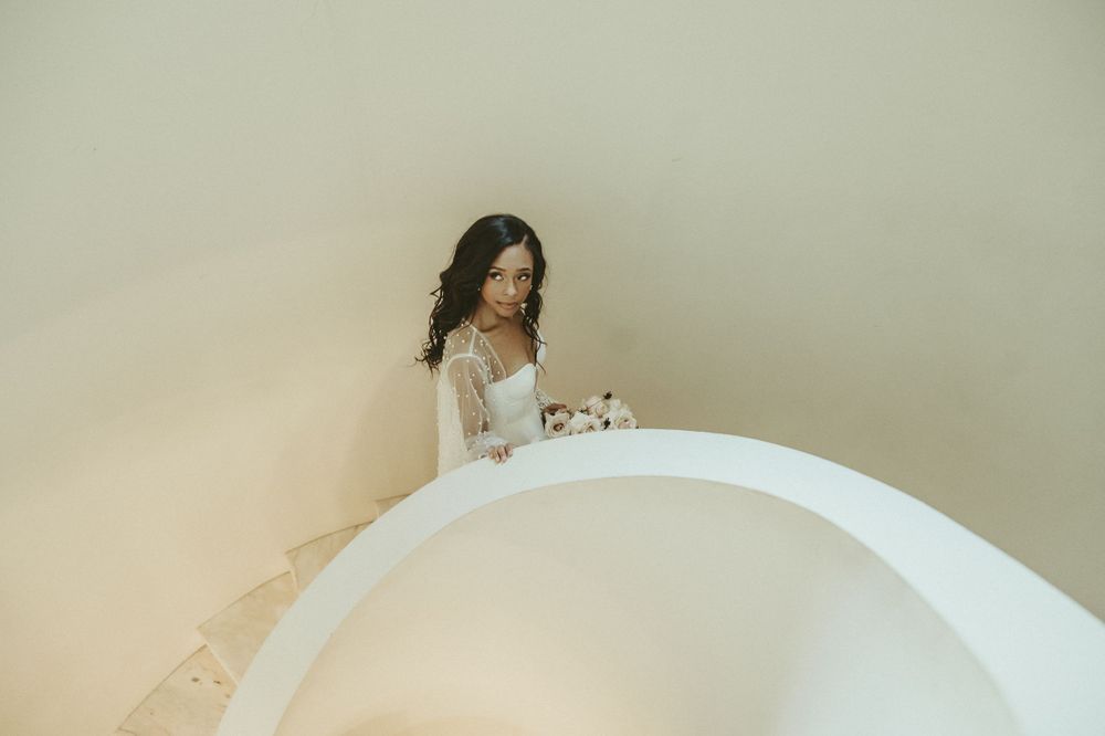 Modern bridal portrait on curved white staircase with minimalist architecture.