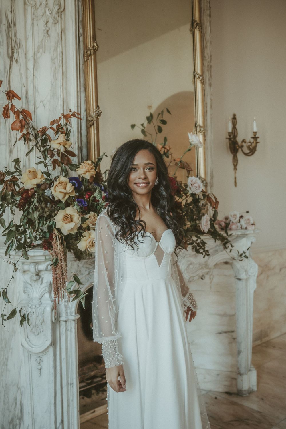 Elegant bridal portrait by vintage fireplace with cascading floral arrangements.