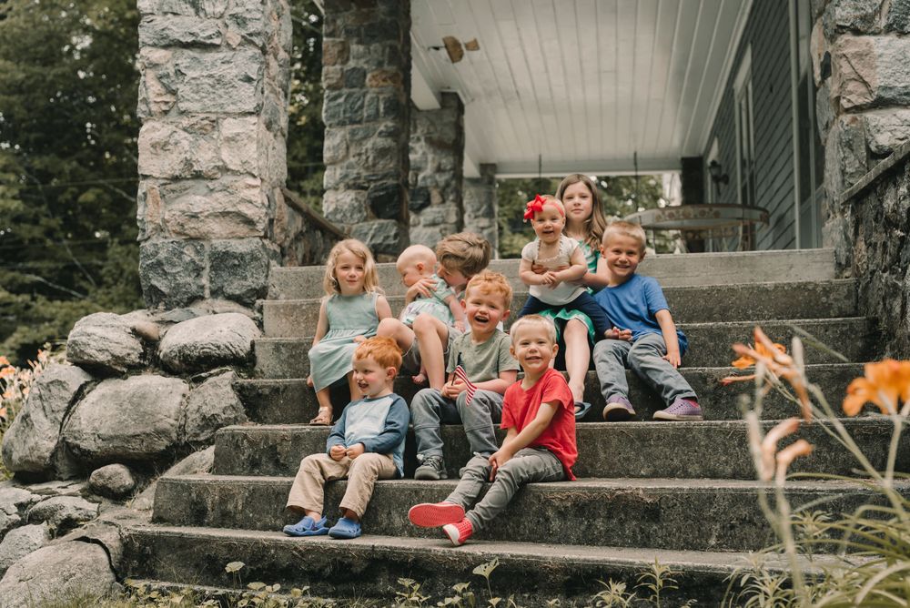 A group gathered on stone steps of a rustic building during an outdoor family gathering.