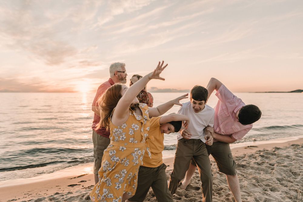 Playful candid moment of group having fun on beach at sunset.