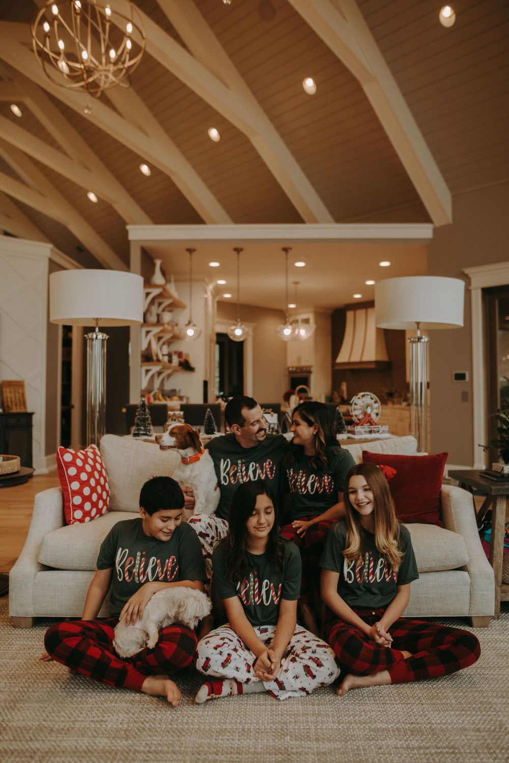 Group wearing matching holiday pajamas gathered on couch in modern rustic living room.