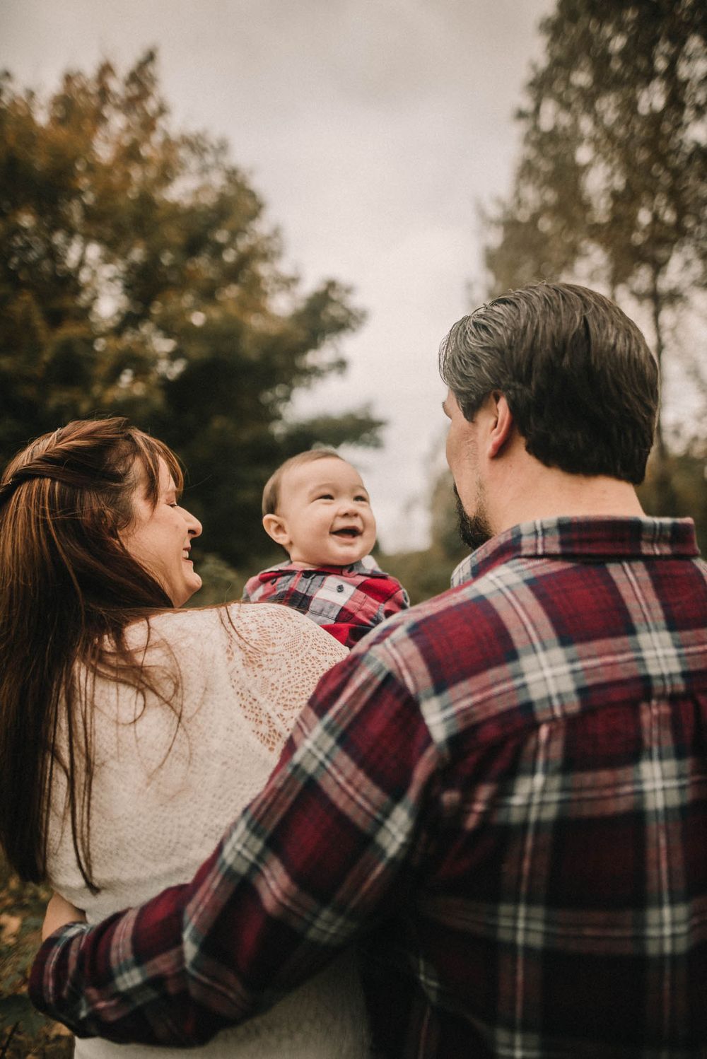 Happy family moment captured with laughing baby outdoors in autumn.