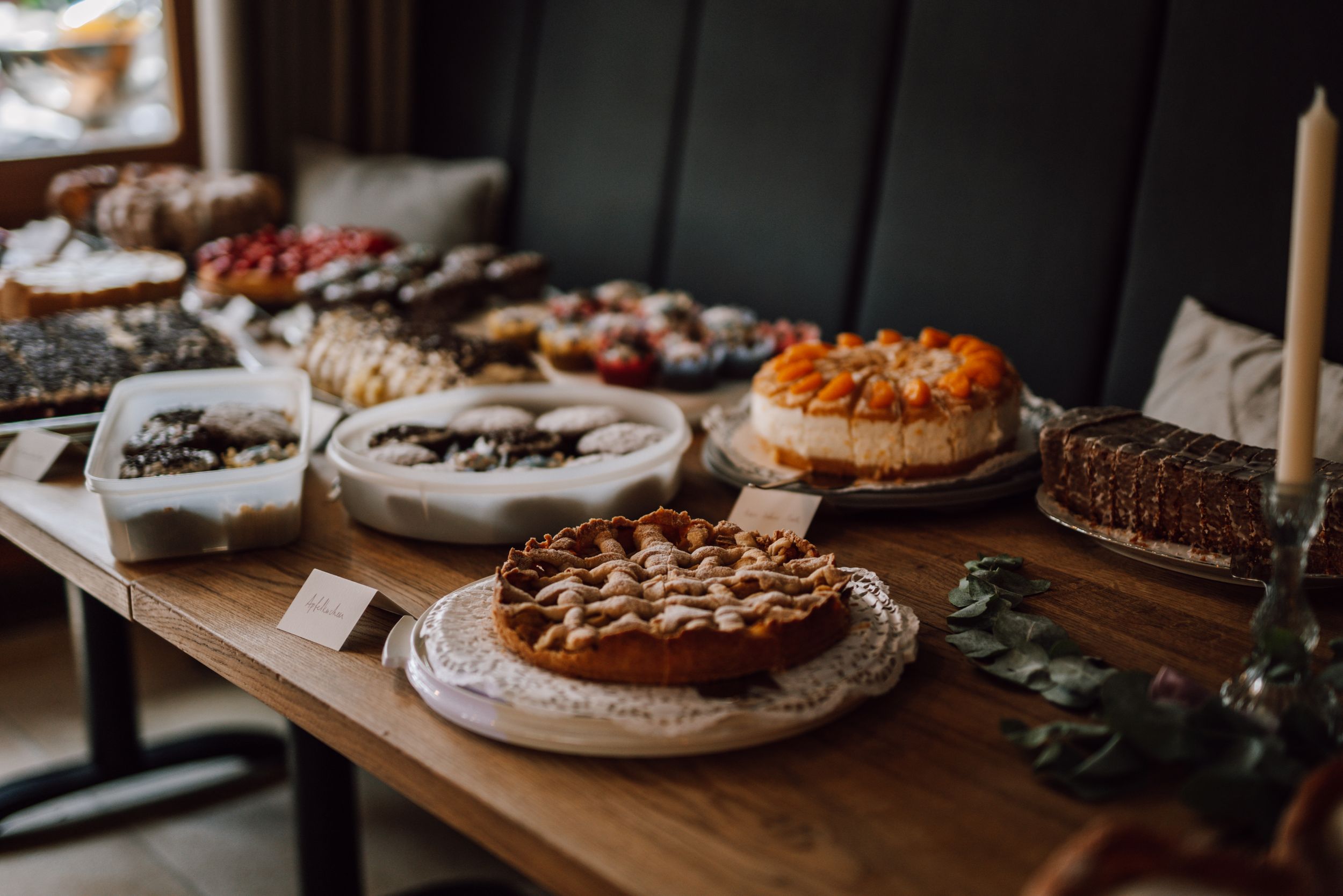 Assorted homemade pies and desserts displayed on wooden table at wedding reception.