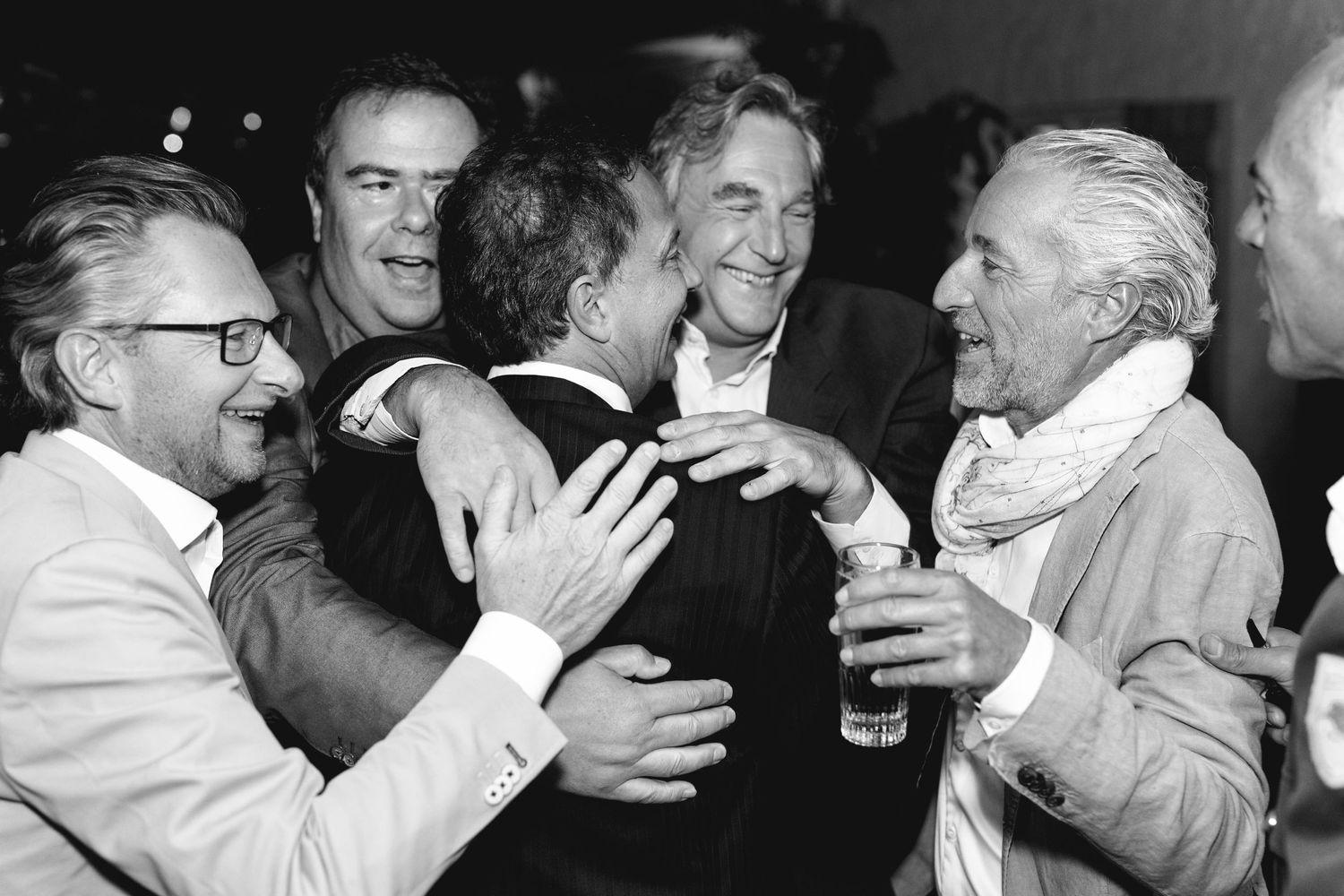 A black and white photo of men laughing and celebrating at a party.