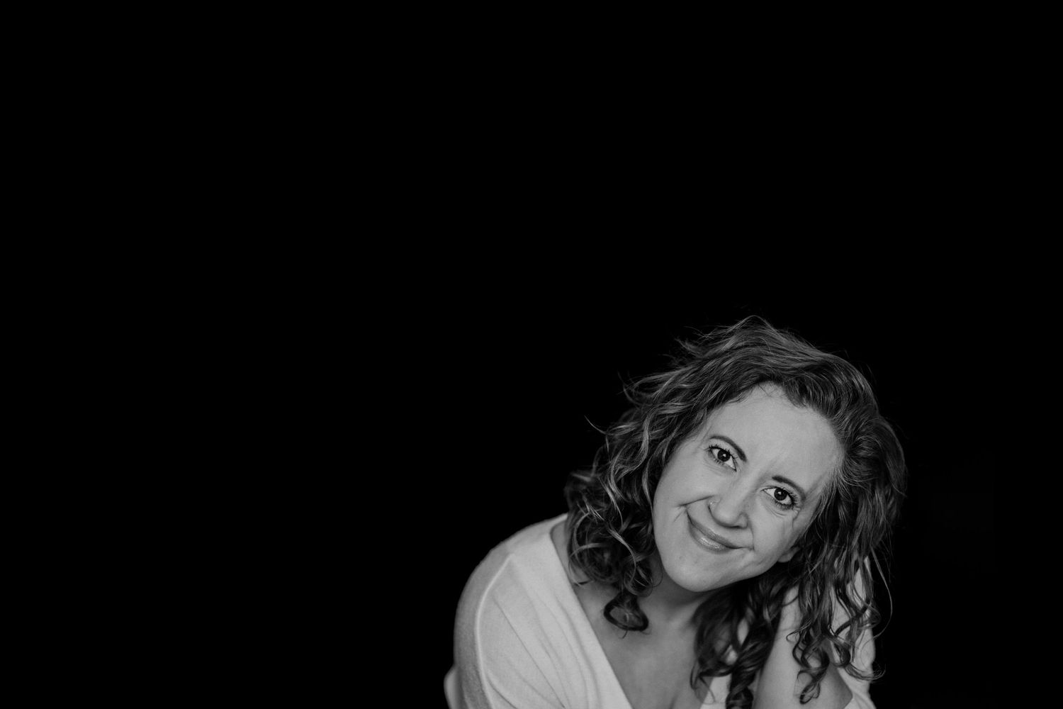 Black-and-white photo of Miranda, a Twin Cities family photographer, smiling at the camera. Miranda is a MN family photographer in Jordan MN
