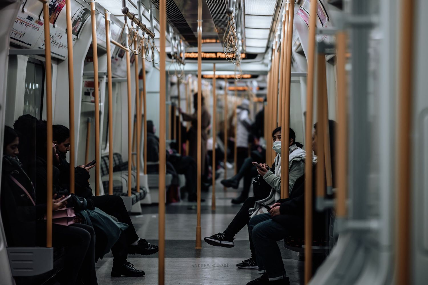 Interior view of a modern subway car with yellow handrails and seats visible.