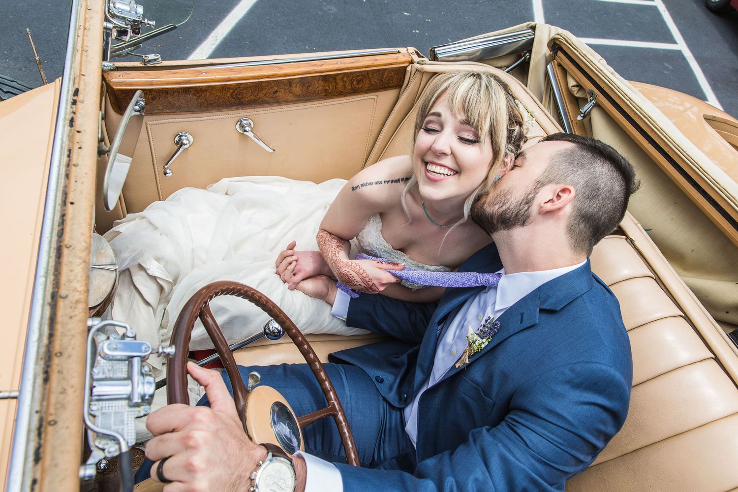Wedding couple sharing intimate moments in vintage car.