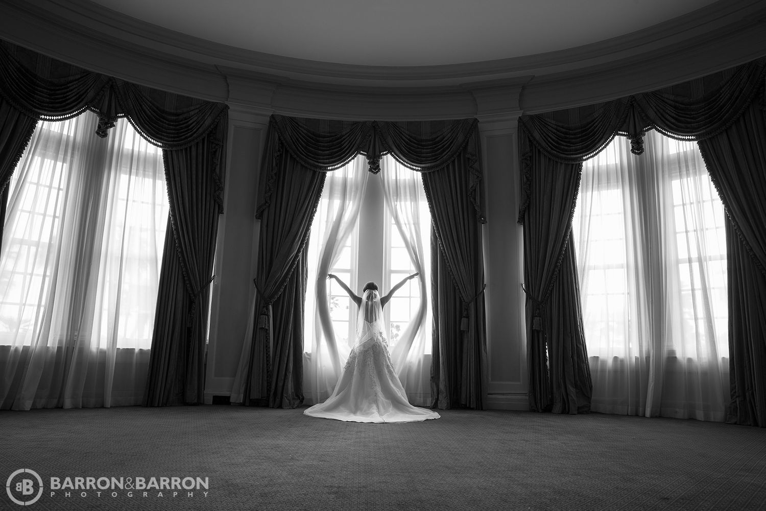 Elegant black and white panorama of a grand ballroom with dramatic window lighting.