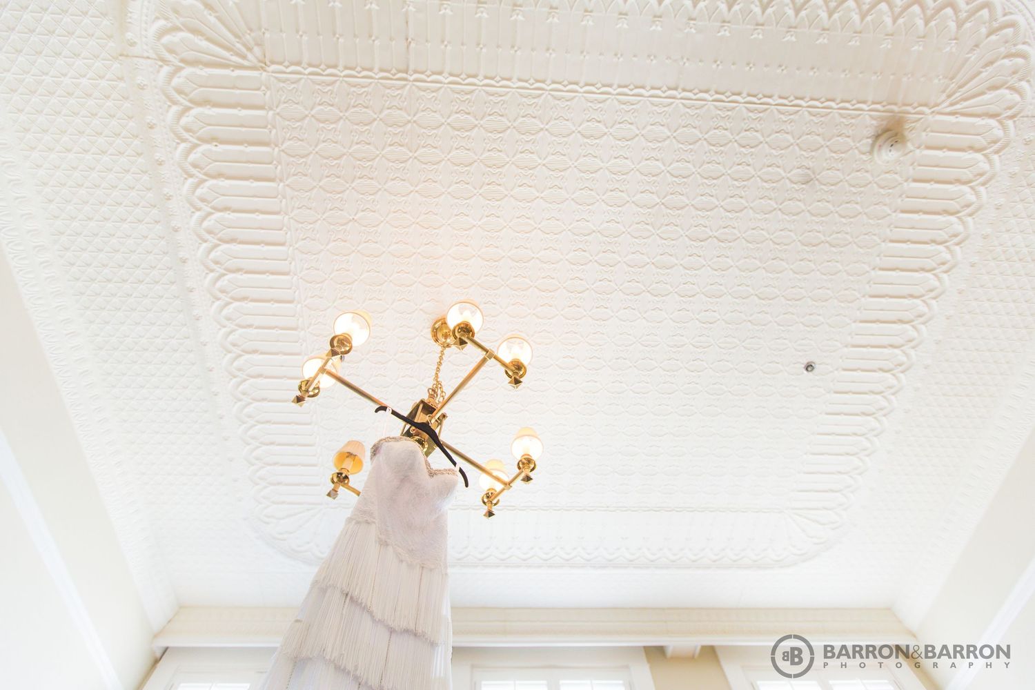 White ornate ceiling detail with vintage architectural patterns and lighting fixtures.