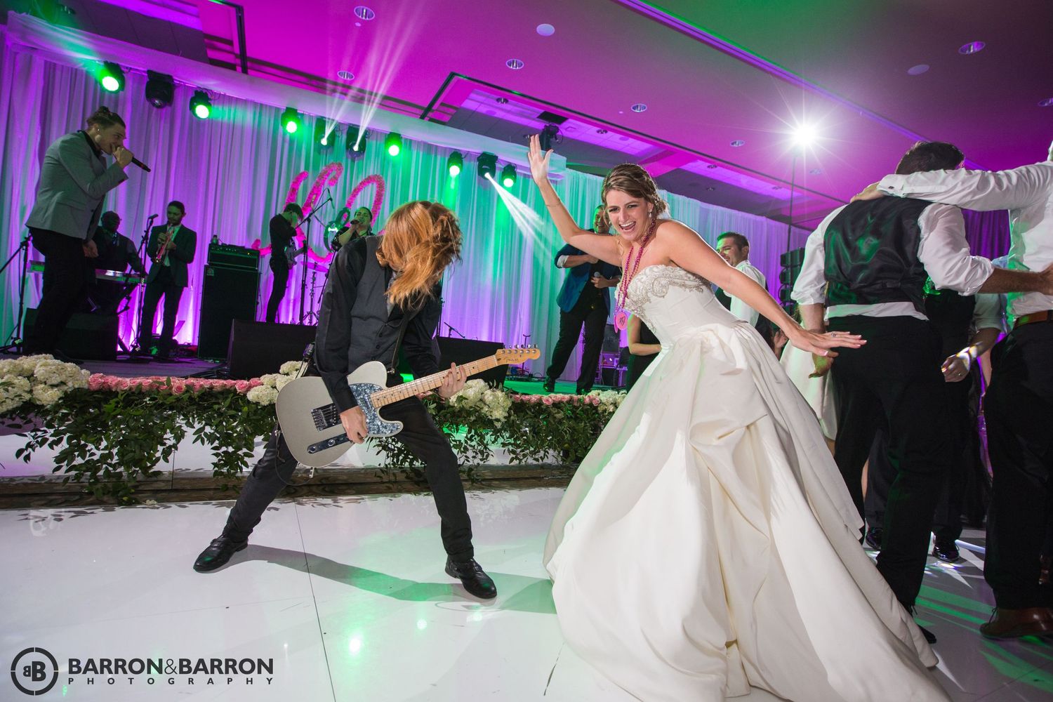 Wedding reception dance floor lit with vibrant purple and green lighting effects.