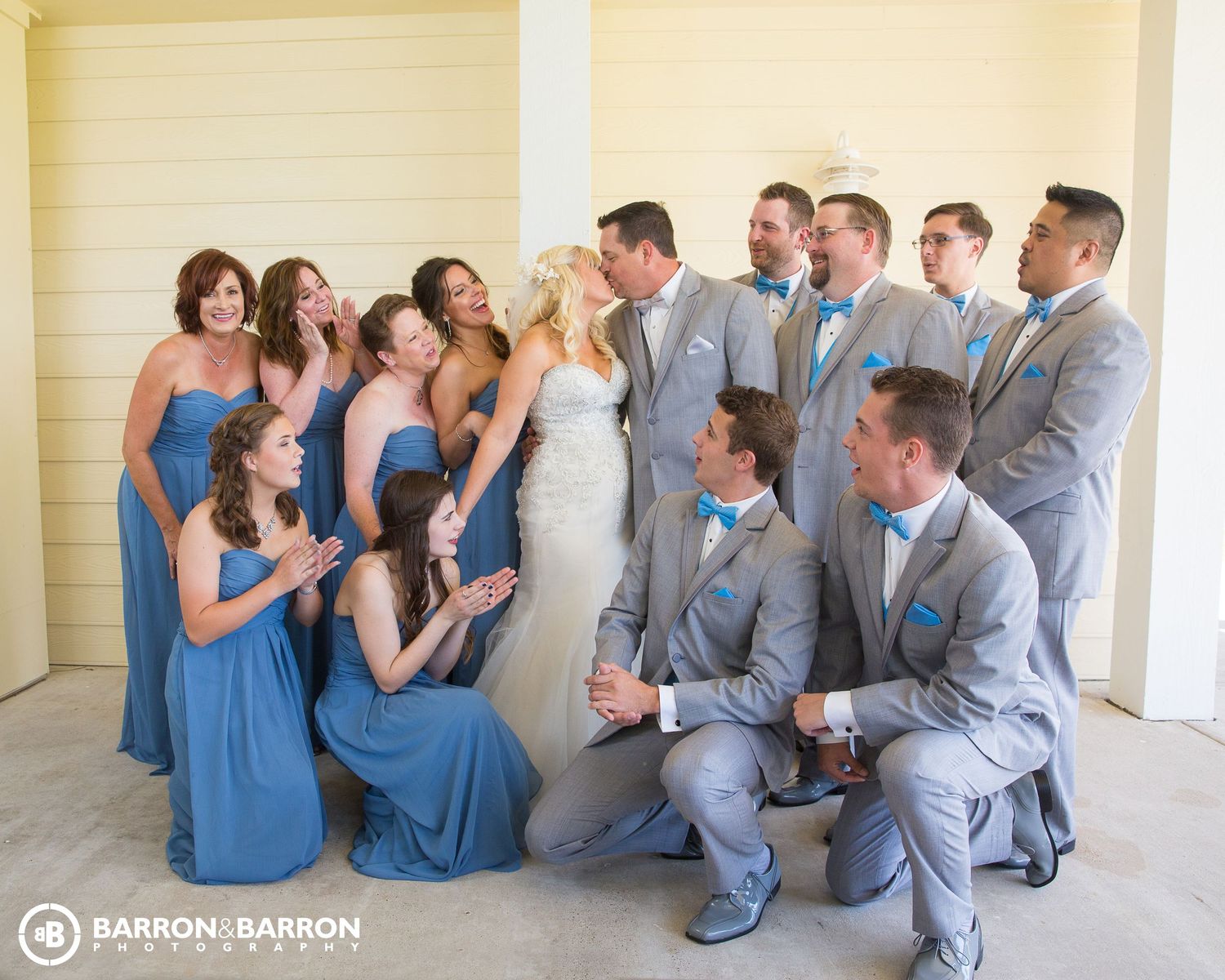 Wedding party in light blue dresses and gray suits posing together outdoors.