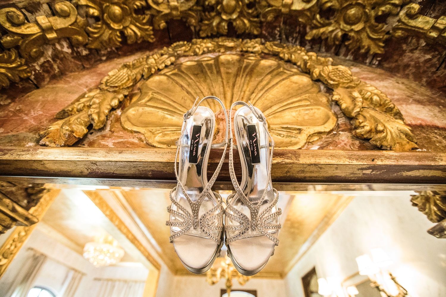 Elegant bridal shoes displayed against ornate golden architectural detail.