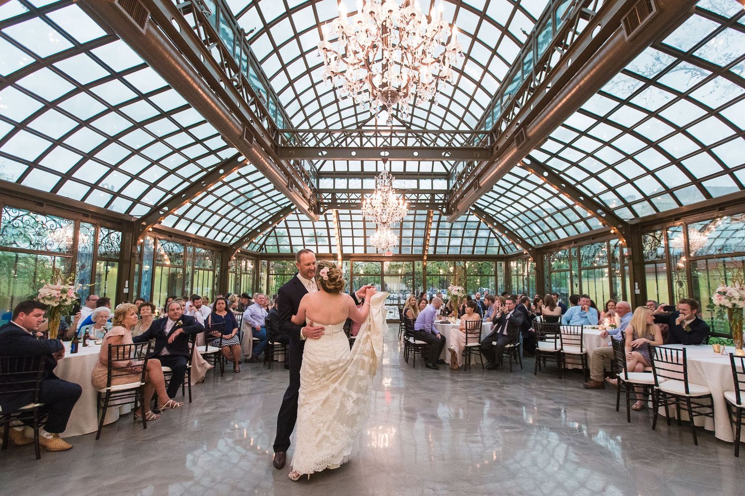 First dance under glass atrium ceiling with crystal chandelier.