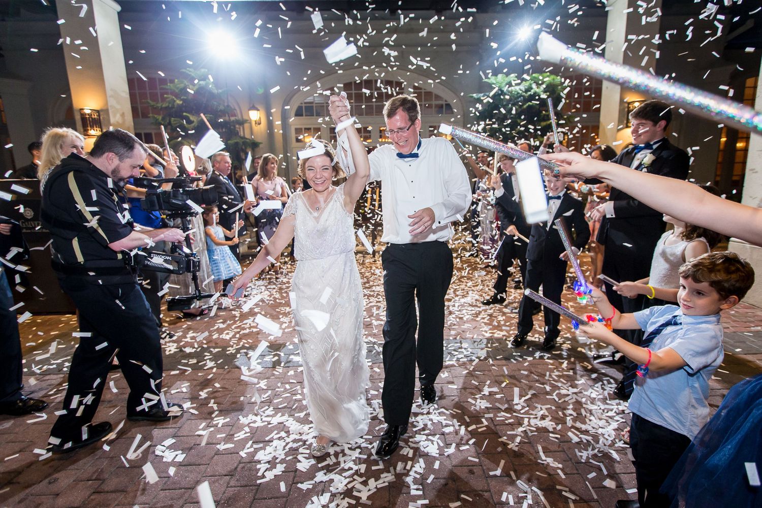Wedding celebration with guests throwing white confetti during an indoor reception.
