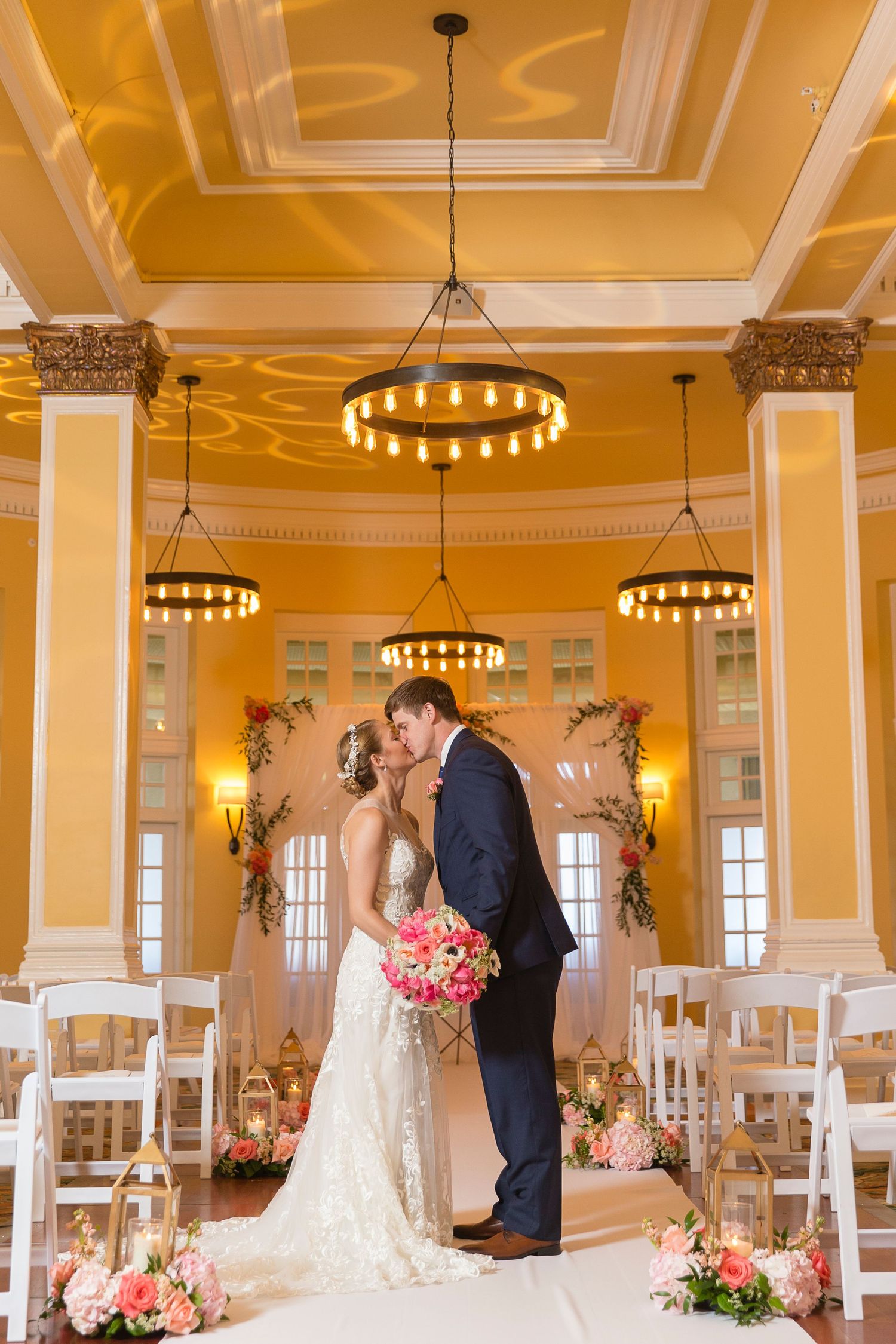 Elegant yellow ballroom with crystal chandeliers set up for a wedding ceremony.