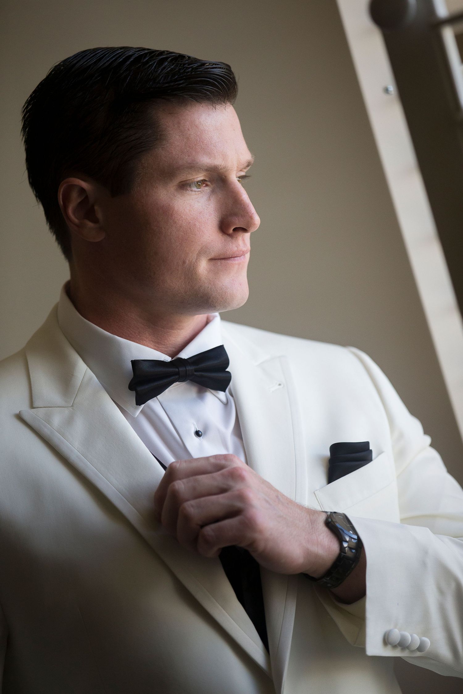 Close-up shots of groom adjusting white tuxedo and bow tie before ceremony.