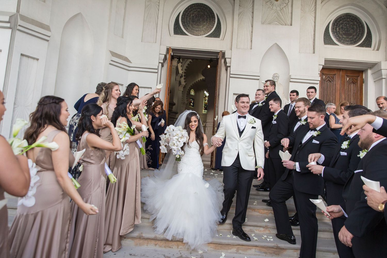 Wedding party celebrating outside historic white church building.