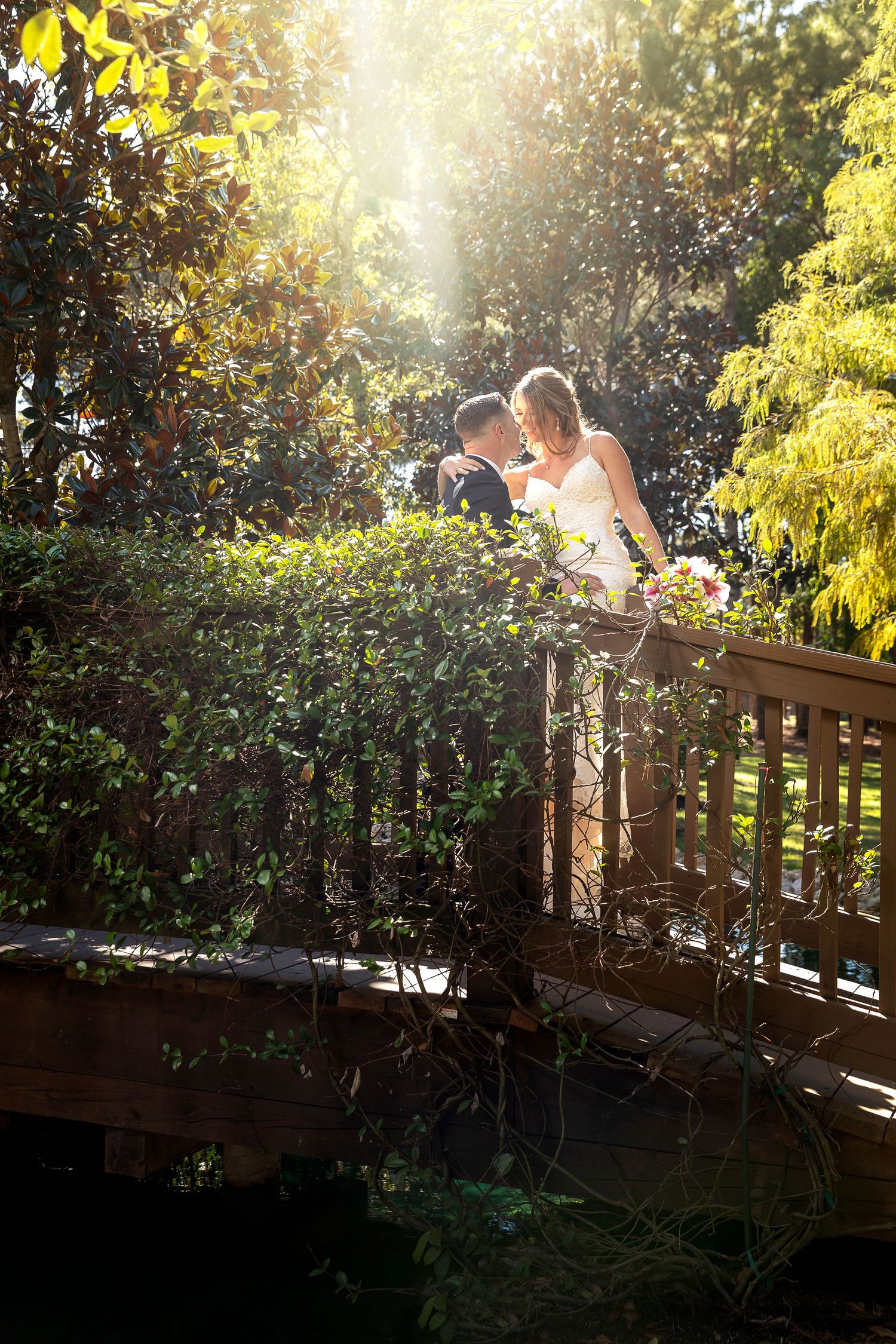 Sunset engagement photo session on a wooden bridge with golden sunlight filtering through trees.