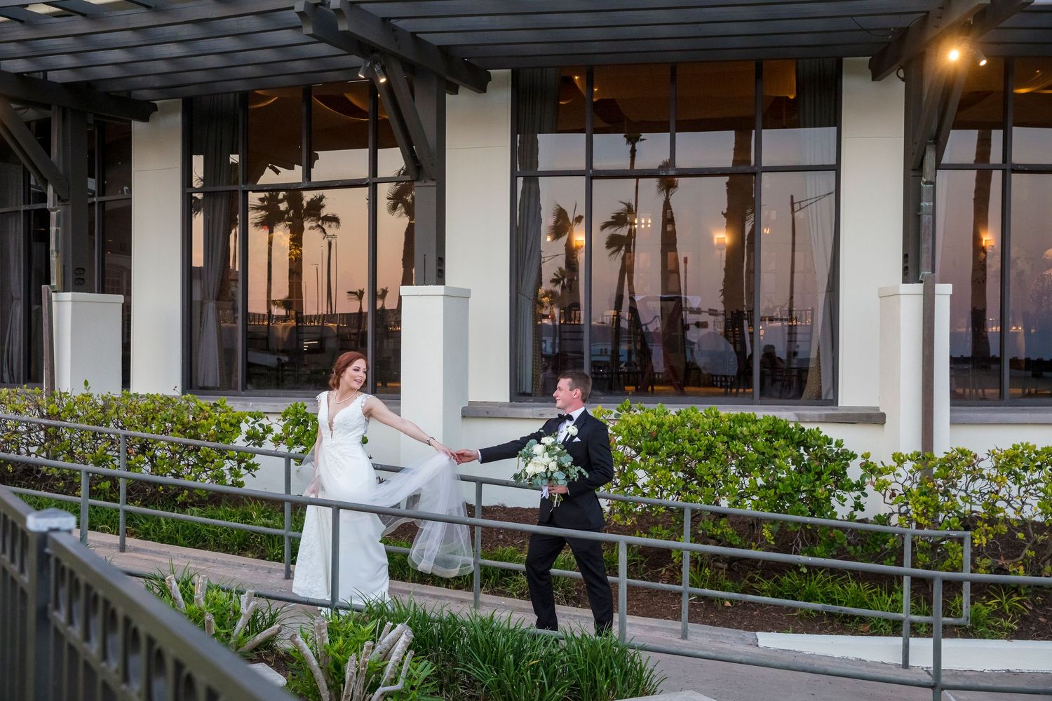 Modern waterfront venue with manicured gardens and outdoor seating areas at dusk.