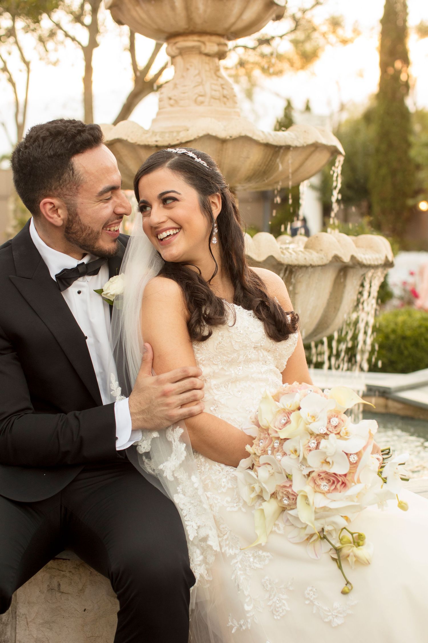 Elegant couple sharing romantic moments at an outdoor wedding reception with orchid centerpieces.