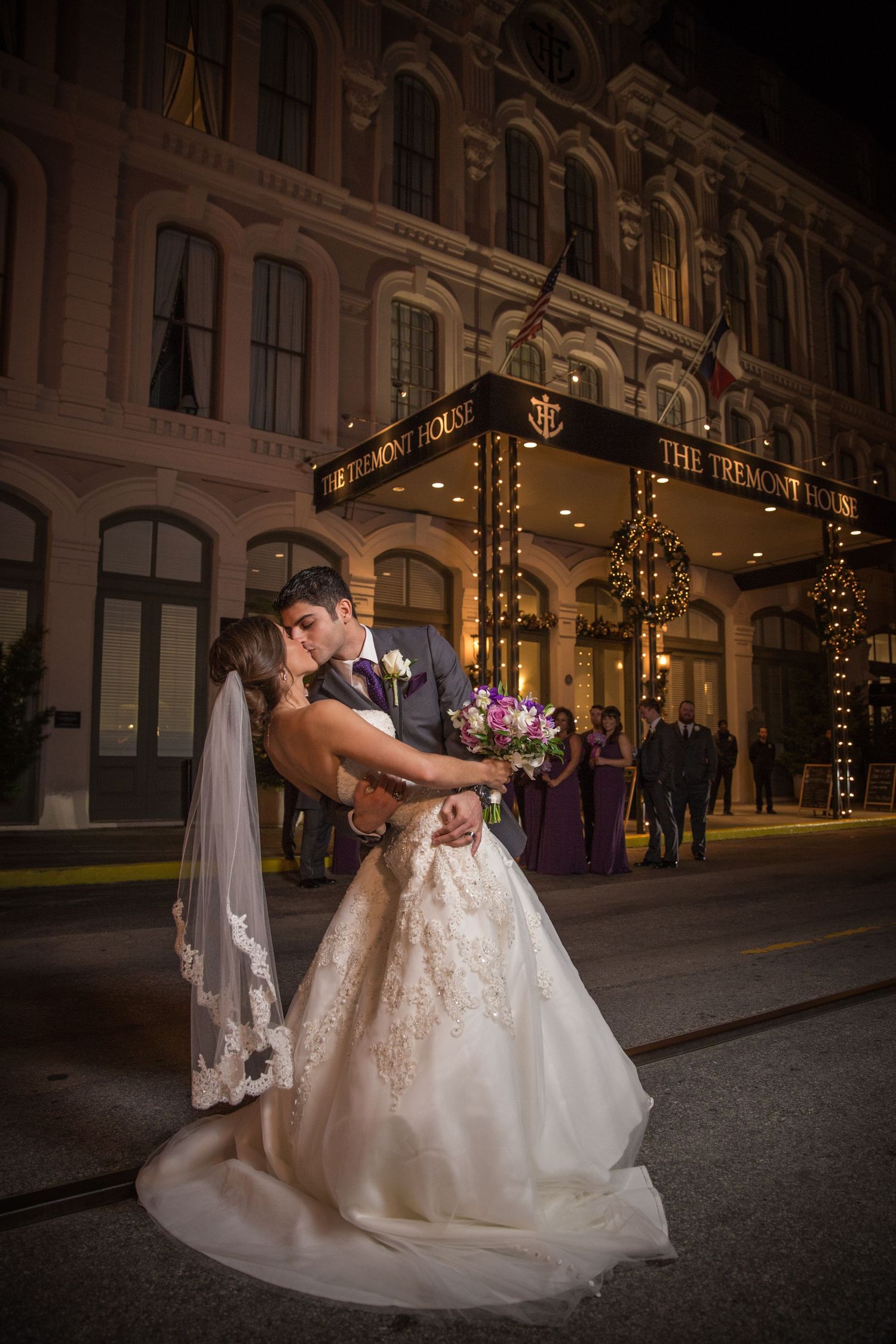 Romantic nighttime wedding photos in front of an illuminated historic building.