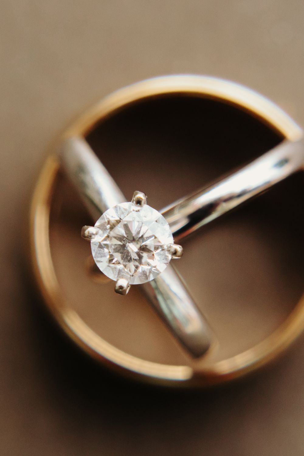 Diamond solitaire engagement ring resting inside gold wedding band closeup.