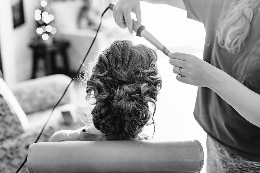 Black and white closeup of elegant bridal updo being styled.