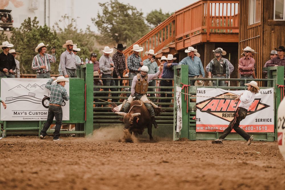 Rodeo arena with wooden bleachers and spectators watching performers on beer barrels.