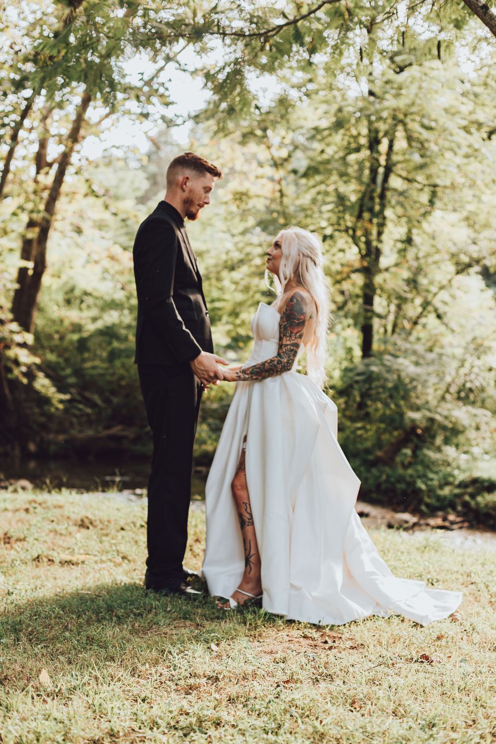A wedding couple sharing an intimate moment in a sunlit forest setting.