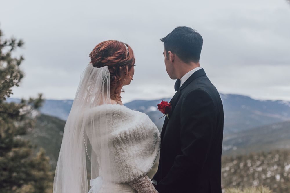 Bride and groom share an intimate moment on a mountaintop with scenic mountain views.