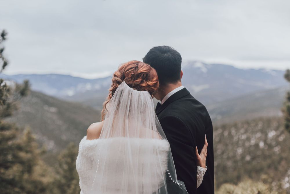 A romantic mountain wedding portrait with the couple embracing against a dramatic landscape.