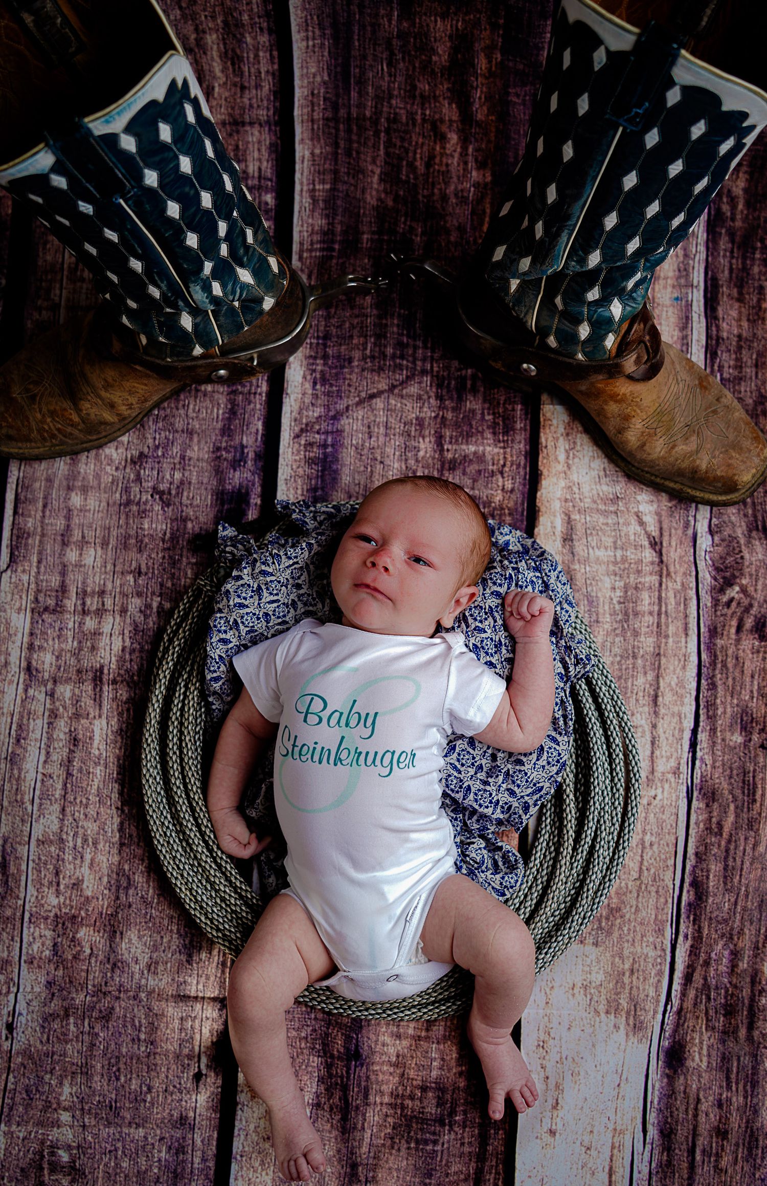 Newborn baby sleeping on blue blanket with polka dot backdrop.