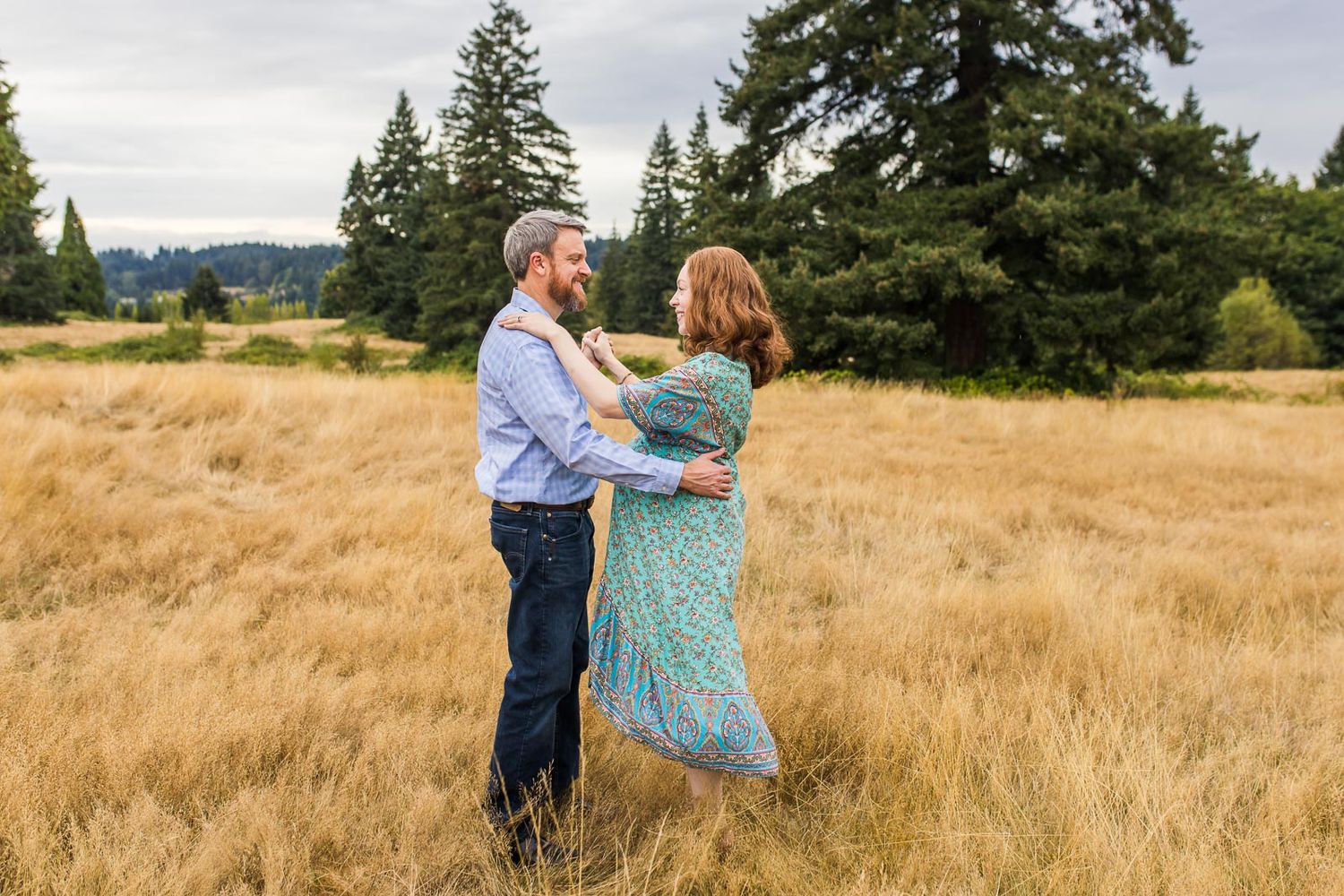 Husband and wife smiling and dancing in a field