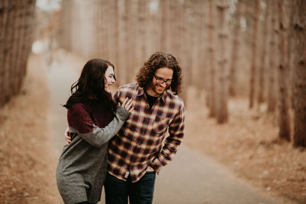 Laughing couple walking together along a wooded path in fall season.