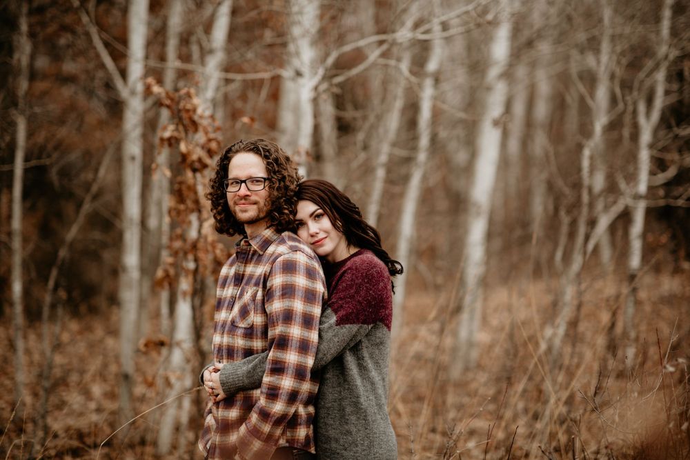 Couple cuddling together in a forest with golden autumn foliage background.