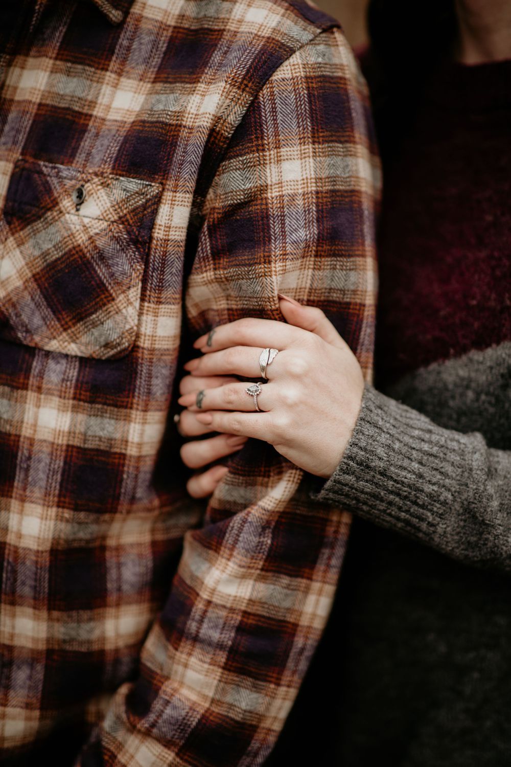 Close-up of womans hand with engagement ring holding mans plaid flannel shirt.